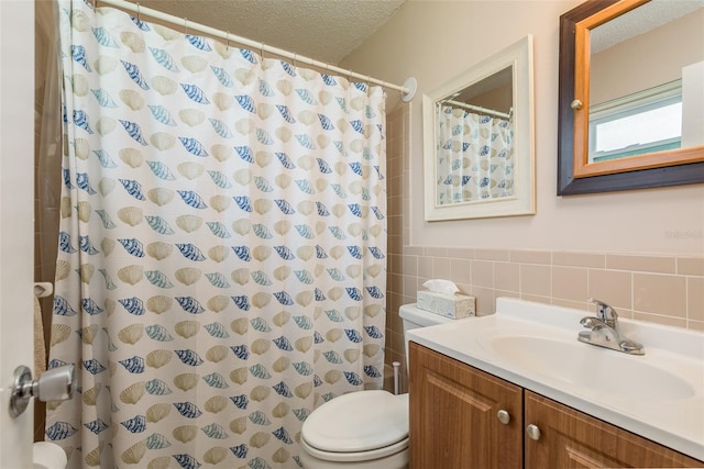 bathroom featuring vanity, toilet, a textured ceiling, walk in shower, and tile walls