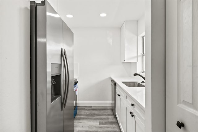 kitchen with white cabinetry, sink, stainless steel appliances, and light hardwood / wood-style flooring