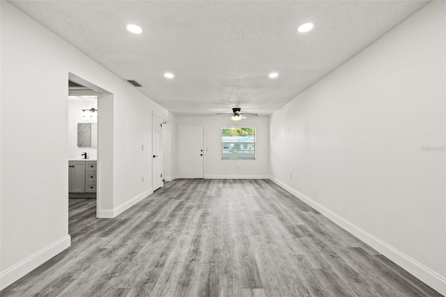 spare room with ceiling fan, light hardwood / wood-style flooring, and a textured ceiling