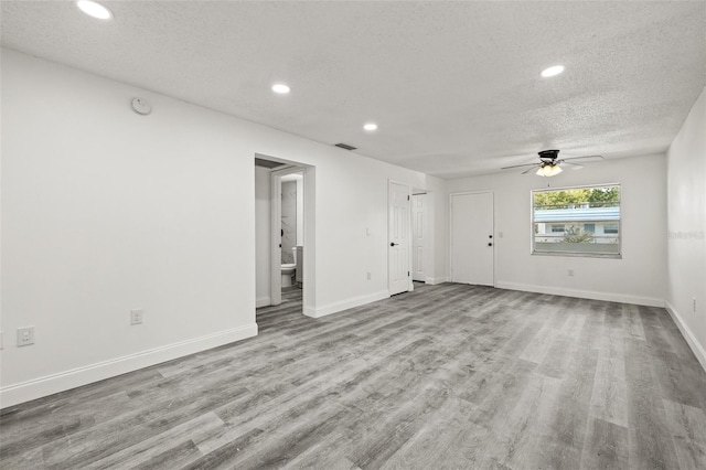 unfurnished living room featuring ceiling fan, a textured ceiling, and light wood-type flooring