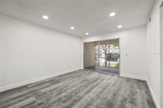 spare room with a textured ceiling and hardwood / wood-style flooring