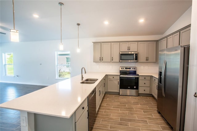 kitchen with kitchen peninsula, appliances with stainless steel finishes, light wood-type flooring, vaulted ceiling, and pendant lighting