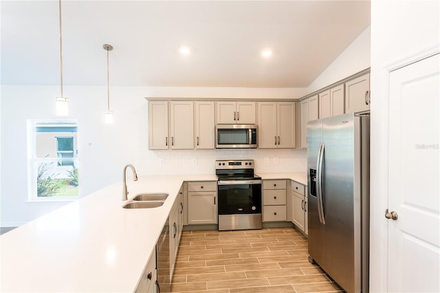 kitchen featuring sink, light hardwood / wood-style floors, pendant lighting, lofted ceiling, and appliances with stainless steel finishes