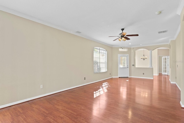 empty room with hardwood / wood-style flooring, ceiling fan with notable chandelier, and crown molding