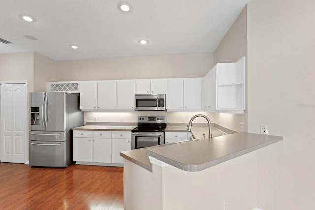 kitchen featuring kitchen peninsula, appliances with stainless steel finishes, white cabinetry, and wood-type flooring