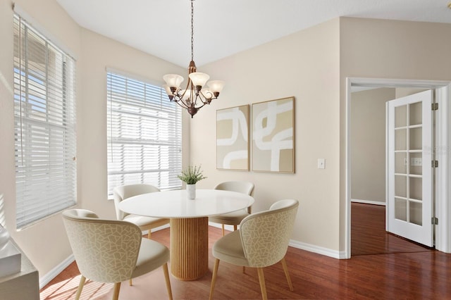 dining area featuring a chandelier, a wealth of natural light, dark wood-type flooring, and lofted ceiling