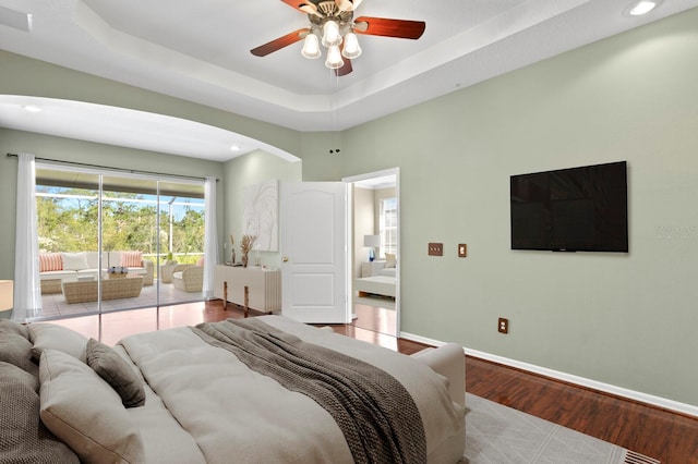 bedroom featuring ceiling fan, light hardwood / wood-style floors, a raised ceiling, and access to outside