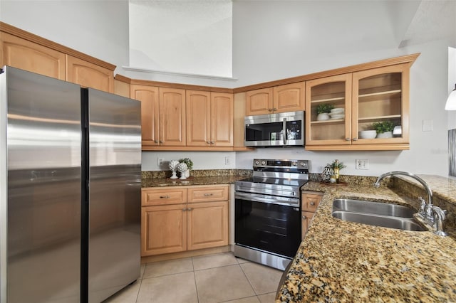 kitchen featuring light tile patterned flooring, appliances with stainless steel finishes, dark stone counters, and sink