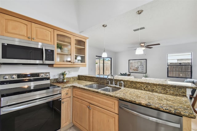 kitchen with kitchen peninsula, stone countertops, stainless steel appliances, and sink