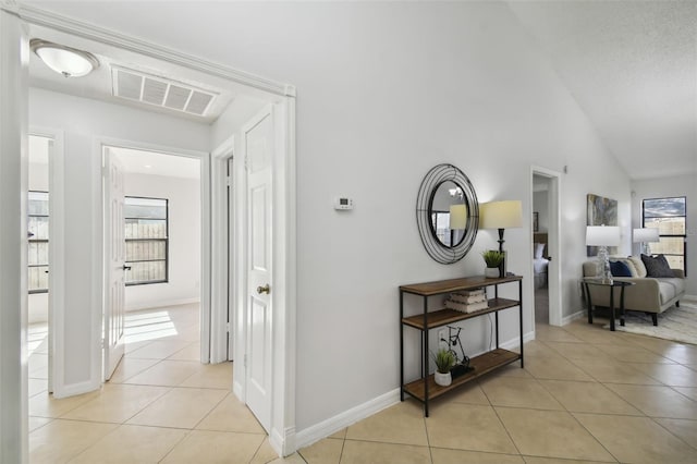 corridor with light tile patterned floors and vaulted ceiling