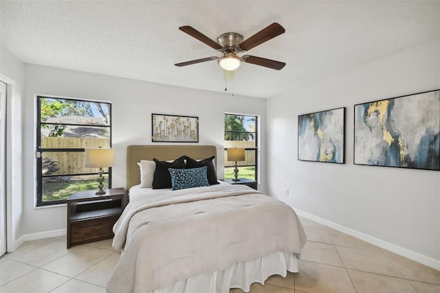 tiled bedroom with ceiling fan and a textured ceiling