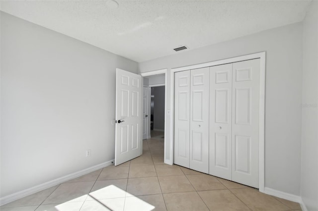 unfurnished bedroom featuring light tile patterned floors, a textured ceiling, and a closet