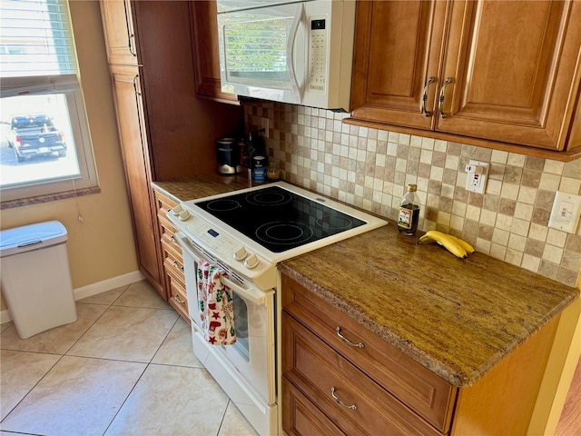 kitchen featuring decorative backsplash, a wealth of natural light, light tile patterned floors, and white appliances