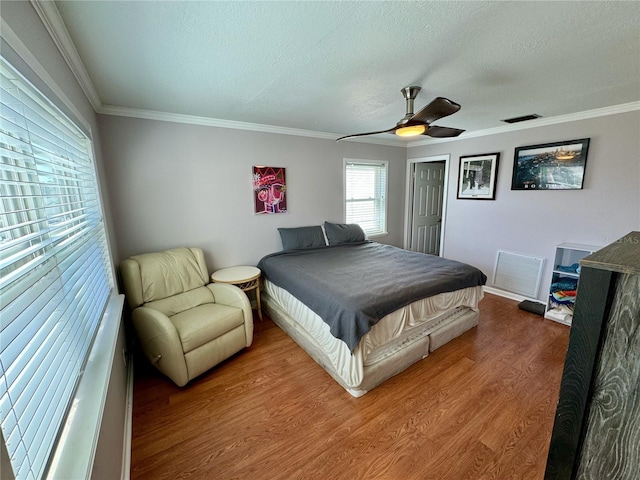 bedroom featuring wood-type flooring, a textured ceiling, ceiling fan, and ornamental molding