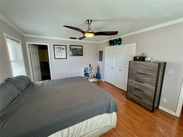 bedroom with ceiling fan, ornamental molding, a textured ceiling, wood-type flooring, and a closet