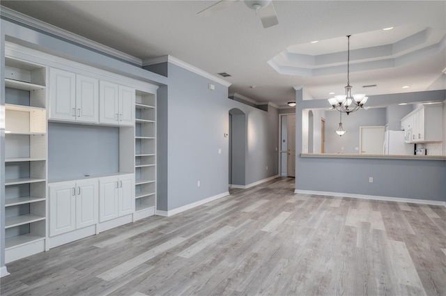 unfurnished living room featuring a raised ceiling, ceiling fan with notable chandelier, light hardwood / wood-style flooring, and crown molding