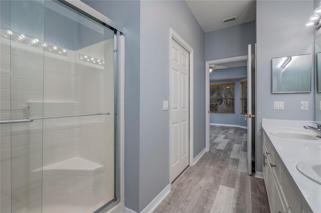 bathroom featuring vanity, hardwood / wood-style flooring, a shower with door, and ceiling fan