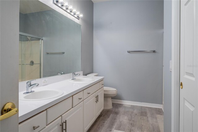 bathroom with wood-type flooring, vanity, toilet, and walk in shower