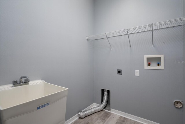 laundry area with hookup for an electric dryer, hookup for a washing machine, light wood-type flooring, and sink