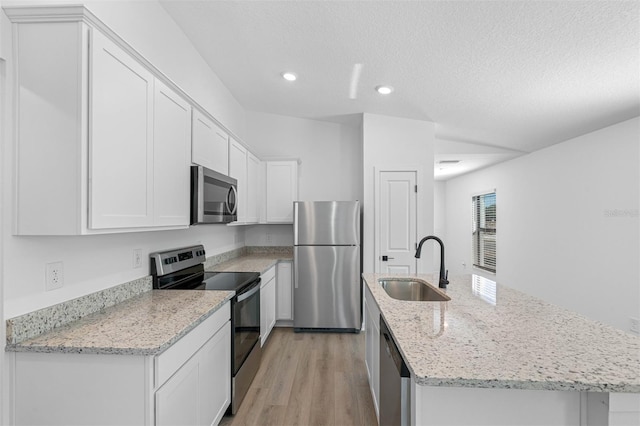 kitchen featuring sink, light hardwood / wood-style flooring, a textured ceiling, appliances with stainless steel finishes, and white cabinetry