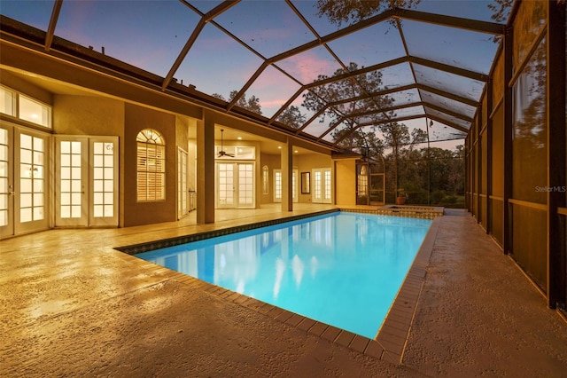 pool at dusk featuring ceiling fan, a lanai, a patio, and french doors