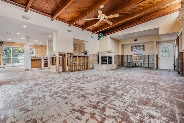 unfurnished living room with ceiling fan, a multi sided fireplace, beam ceiling, and wooden ceiling