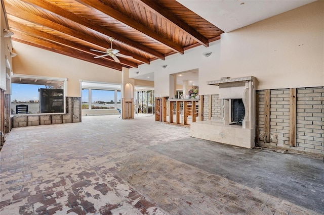 unfurnished living room featuring high vaulted ceiling, ceiling fan, wood ceiling, a brick fireplace, and beam ceiling