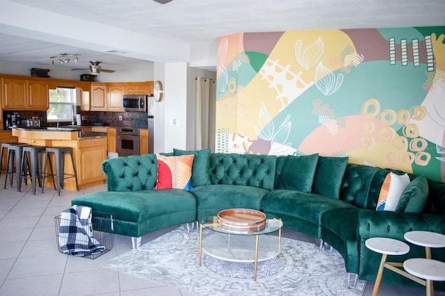 living room featuring light tile patterned floors, beam ceiling, ceiling fan, and sink