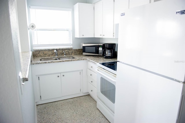 kitchen with white appliances, white cabinetry, and sink