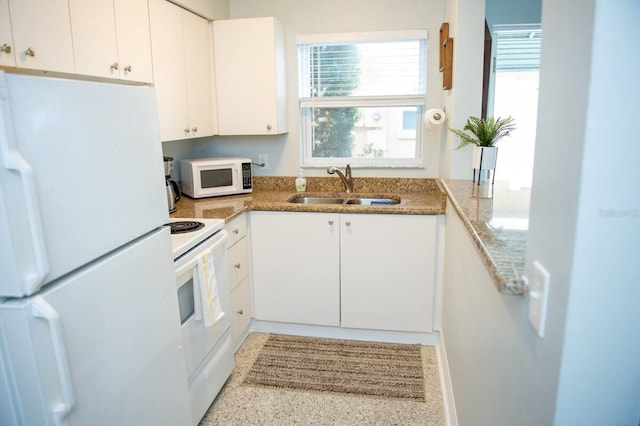 kitchen with white cabinetry, sink, light stone countertops, and white appliances