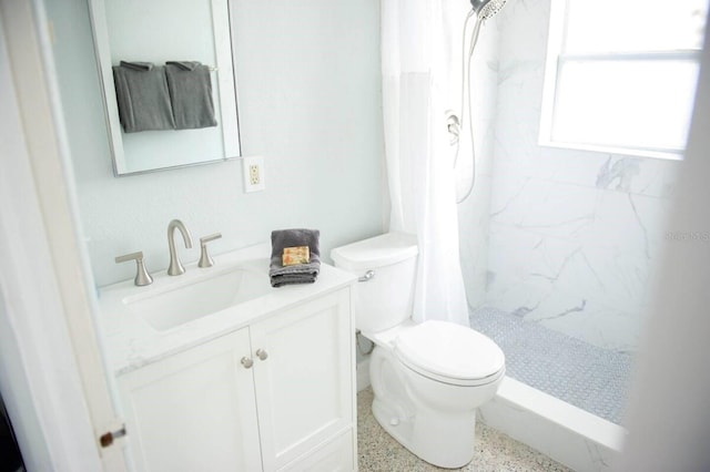 bathroom featuring a tile shower, vanity, and toilet