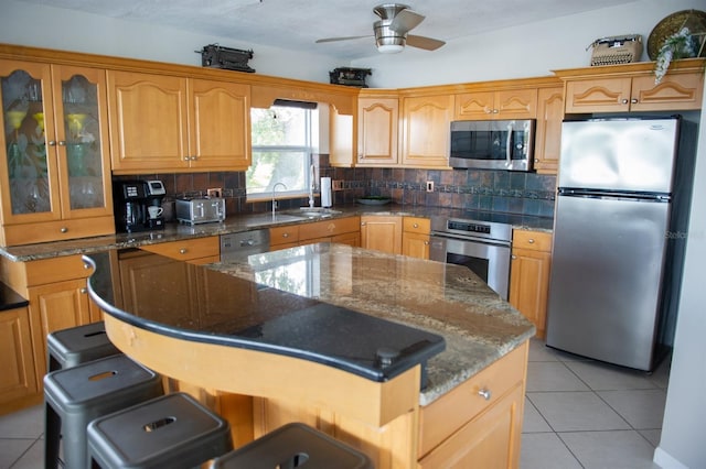 kitchen with a breakfast bar, a center island, dark stone countertops, tasteful backsplash, and stainless steel appliances