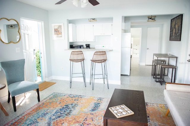 kitchen with a breakfast bar, white cabinets, ceiling fan, white fridge, and kitchen peninsula