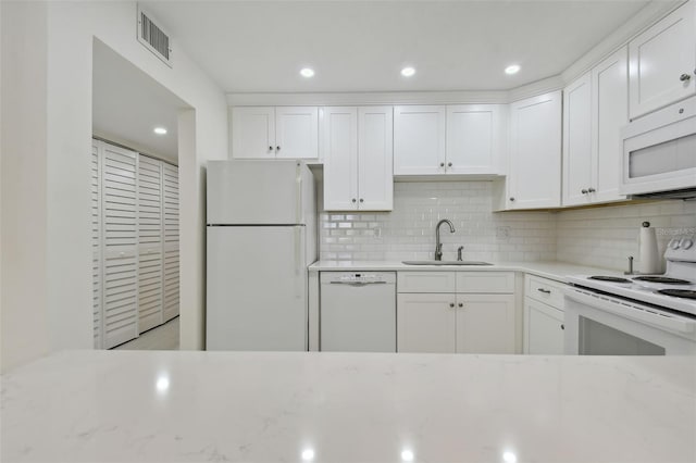 kitchen featuring decorative backsplash, white appliances, white cabinetry, and sink