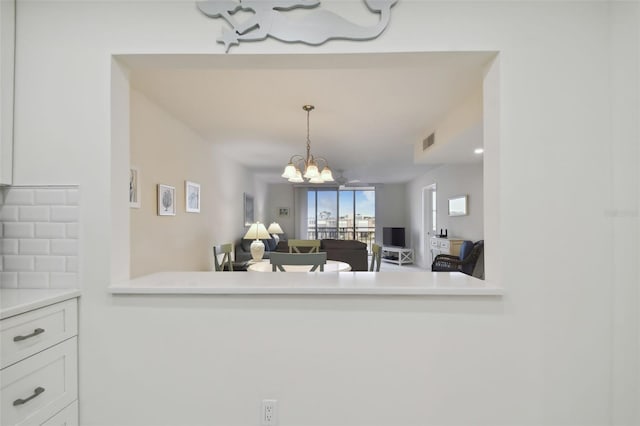 kitchen with kitchen peninsula, white cabinets, hanging light fixtures, and a notable chandelier