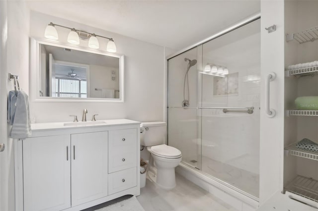 bathroom with vanity, ceiling fan, toilet, and a shower with shower door