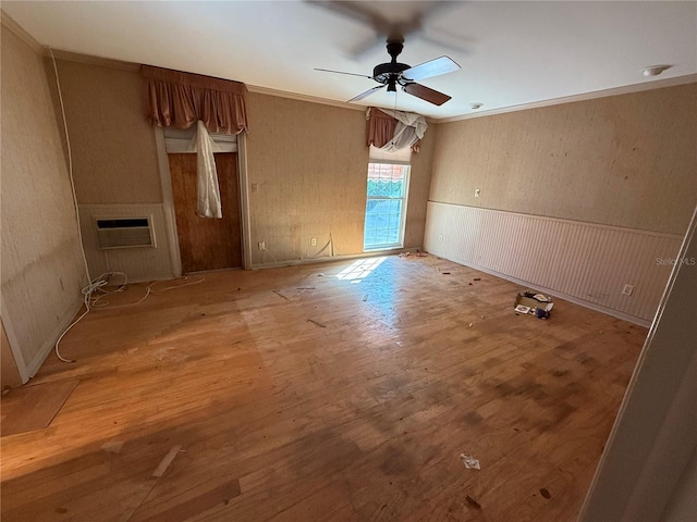 empty room with a wall mounted air conditioner, ornamental molding, ceiling fan, wooden walls, and wood-type flooring