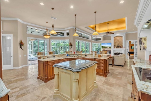 kitchen featuring decorative light fixtures, ceiling fan, a spacious island, and light stone countertops