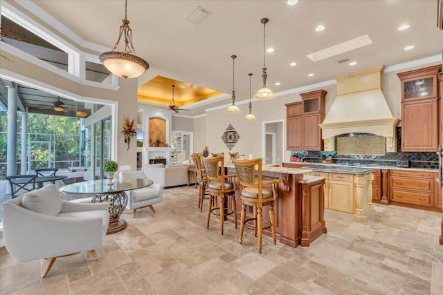 kitchen with a center island, tasteful backsplash, pendant lighting, a fireplace, and custom range hood