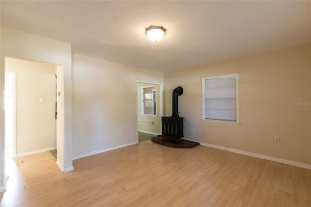 unfurnished living room featuring a wood stove and light wood-type flooring