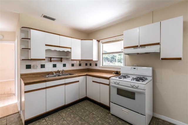 kitchen featuring white gas stove, white cabinetry, sink, and tasteful backsplash