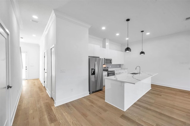 kitchen with light stone countertops, pendant lighting, white cabinetry, stainless steel appliances, and an island with sink