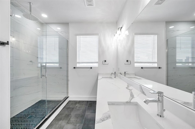 bathroom featuring a shower with door, a healthy amount of sunlight, and vanity