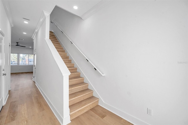 staircase with ornamental molding and hardwood / wood-style floors