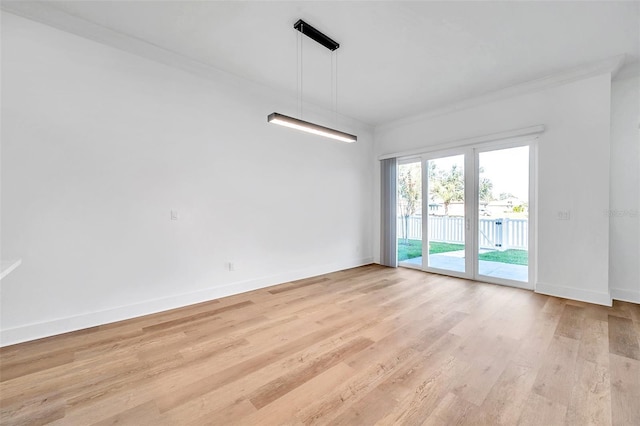 empty room with light hardwood / wood-style floors and crown molding