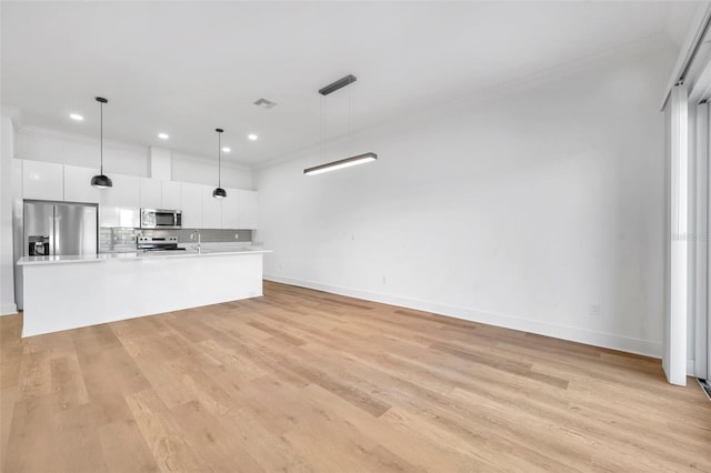 kitchen featuring white cabinetry, an island with sink, appliances with stainless steel finishes, tasteful backsplash, and pendant lighting