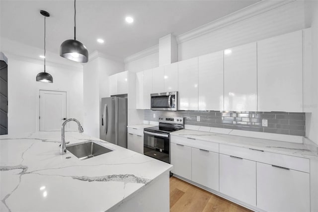 kitchen featuring white cabinetry, sink, stainless steel appliances, and pendant lighting