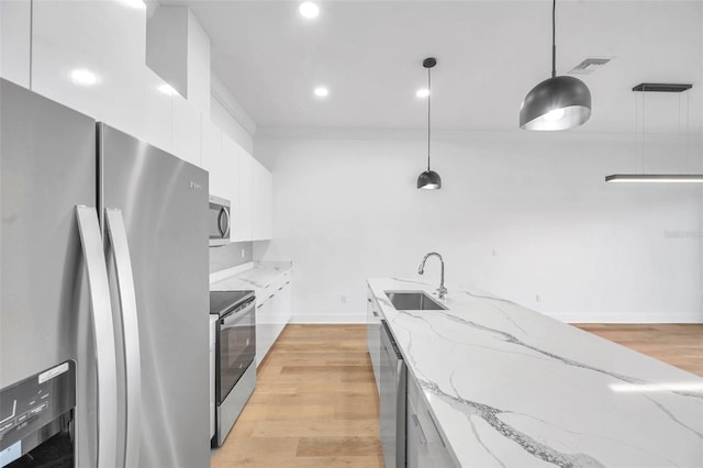 kitchen featuring light stone countertops, pendant lighting, appliances with stainless steel finishes, white cabinets, and sink