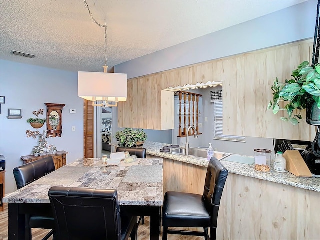 dining space featuring a textured ceiling, light wood-type flooring, and sink