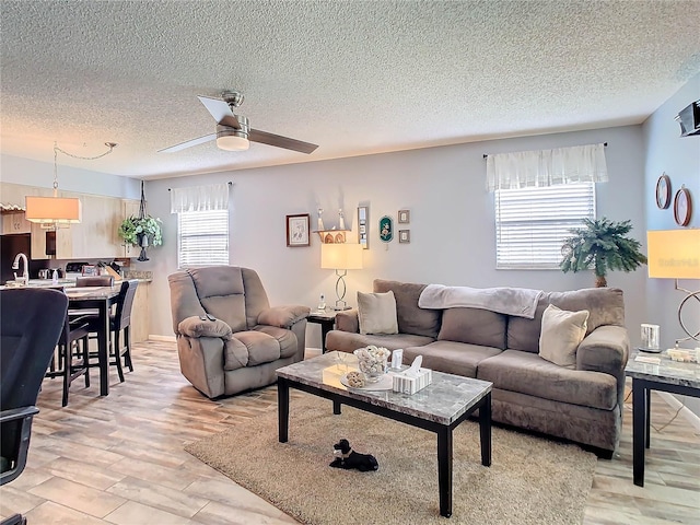 living room featuring plenty of natural light, light hardwood / wood-style floors, a textured ceiling, and ceiling fan